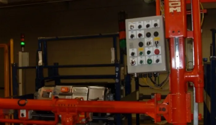 Manipulador naranja con estación de botones en planta