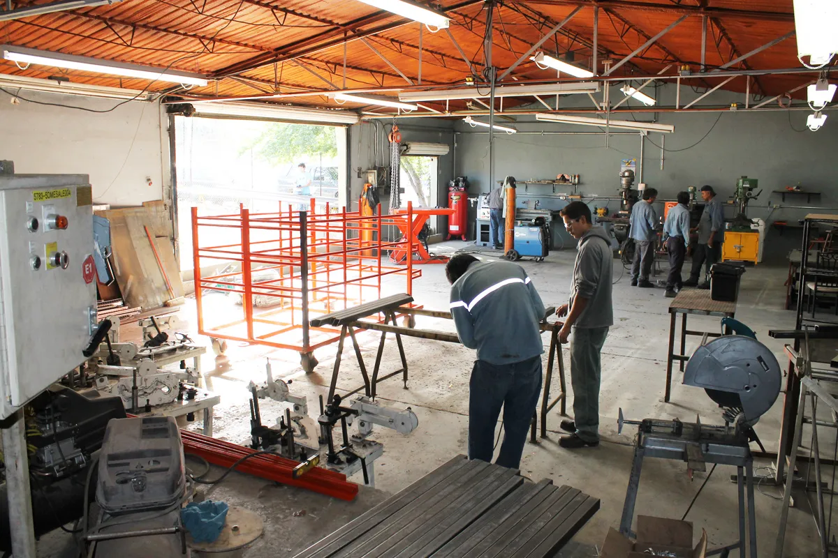 Técnicos trabajando junto a racks naranjas en el taller de ACI